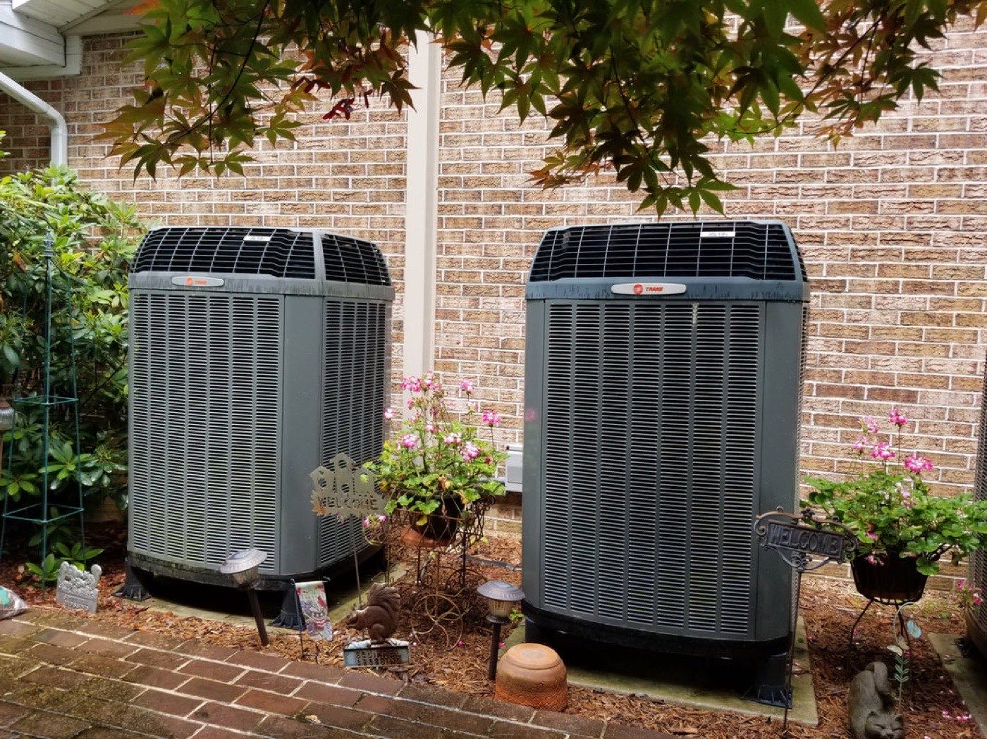 Two Trane outdoor units installed beside a brick home